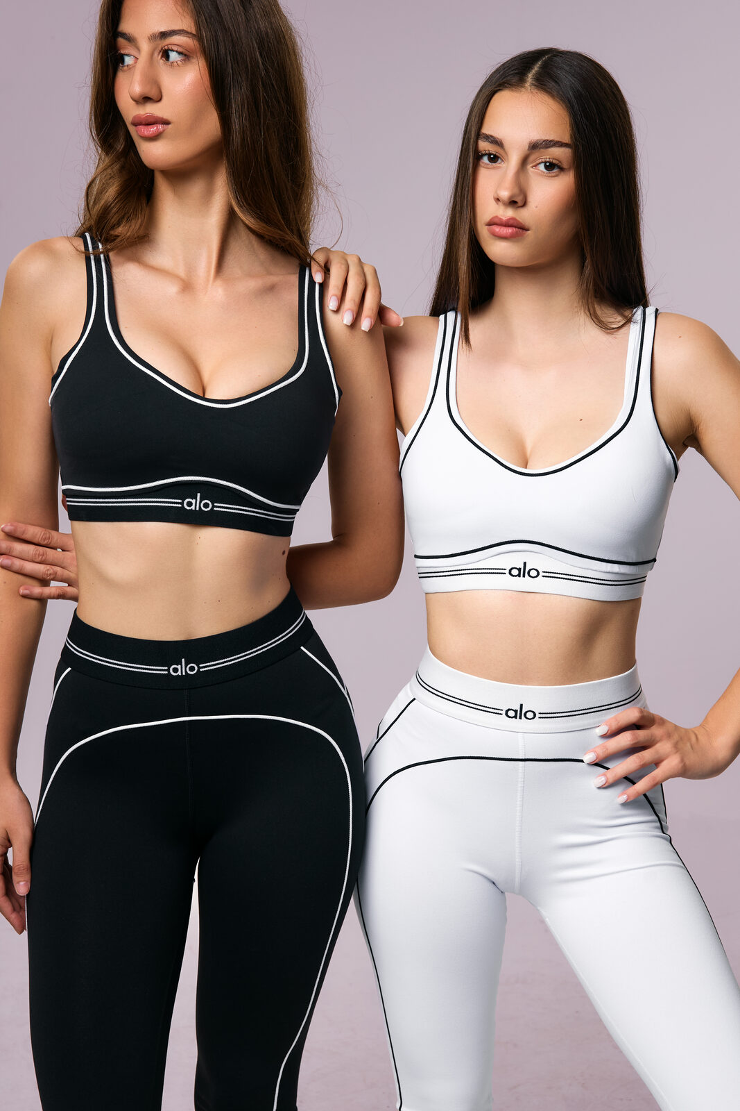 Two models wearing curated black and white activewear sets from the latest ALOMNIO drop